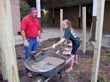 A student setting a post for the metal roof. Darryl Lesak, City of Victoria, looks on.