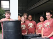 BEAST students pose for a photo with the rain barrels before putting them into place under the metal roof.