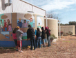 Students painting water cycle on one of the tanks. The organic garden is in the background.